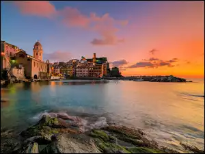 Włoskie miasteczko Vernazza z malowniczymi domami przy skalnym wybrzeżu o zachodzie słońca