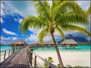 Molo prowadzące do domków na morzu na wyspie Bora Bora na tle gór