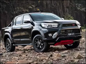 Czarny japoński samochód Toyota Hilux na kamieniach