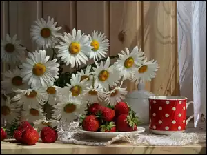 Margerytki z truskawkami na stole przy oknie