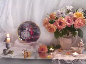 Zapalona świeca obok kwiatów i figurki