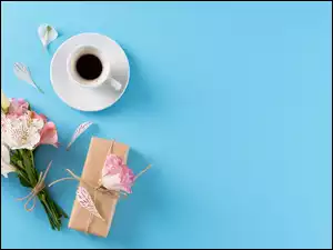 Lilie i eustomy obok prezentu i filiżanki kawy