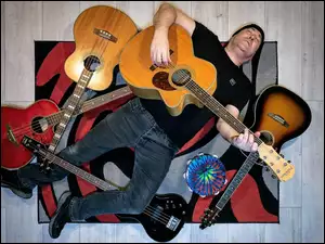 Na dywanie leżący mężczyzna z gitarami
