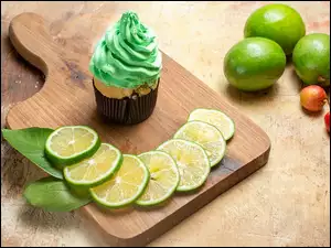Plasterki limonki obok babeczki na desce