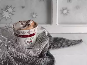 Kubek gorącej czekolady owinięty szarym szalem