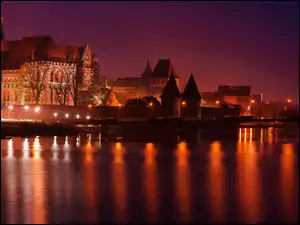 Oświetlony Zamek krzyżacki w Malborku nad rzeką Nogat nocą