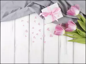 Tulipany na deskach obok prezentu i serduszek