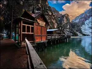 Domy na pomoście nad jeziorem Lago di Braies i osnieżone Dolomity
