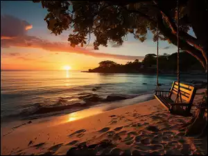 Huśtawka na drzewie na plaży na tle zachodu słońca nad morzem