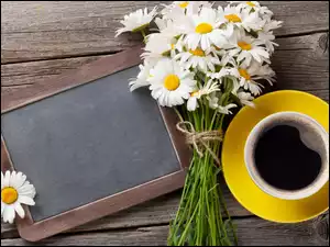 Książka i kwiaty obok filiżanki kawy