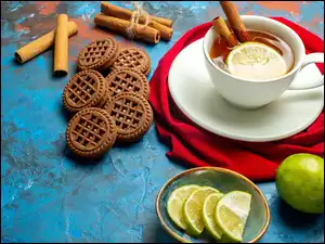 Kompozycja z filiżanką herbaty, ciasteczkami, cytryną i cynamonem