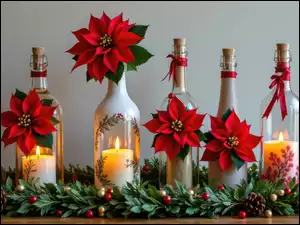 Zapalone świece na butelkach ozdobionych kwiatami gwiazdy betlejemskiej na gałązkach