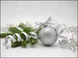 Srebrna bombka z wstążką na iglastej gałązce