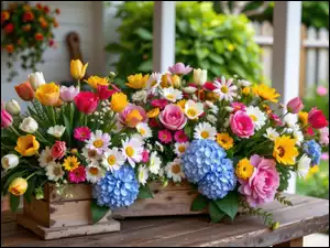 Różne kolorowe kwiaty w skrzynce na stole przed domem w ogrodzie