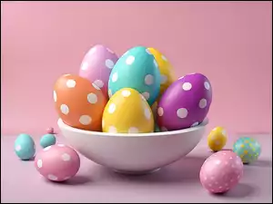 Kolorowe jajka wielkanocne w kropki w białej misie na różowym tle