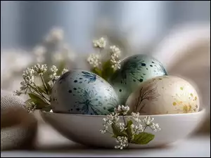 Trzy pisanki i drobne białe kwiaty w misce