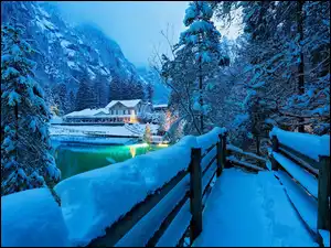 Wieczór, Góry, Światła, Szwajcaria, Jezioro Blausee, Zima, Lasy, Dom, Alpy, Ośnieżone, Drzewa, Most