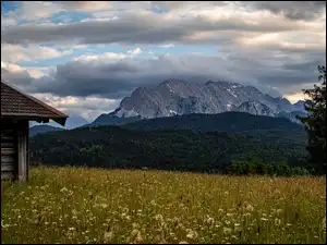 Szopa na łące i chmury nad Alpami
