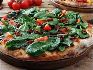 Pizza z pomidorami i szpinakiem na desce