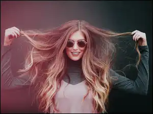 Uśmiechnięta długowłosa kobieta w okularach