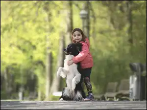 Dziewczynka przytula swojego pieska rasy Border collie